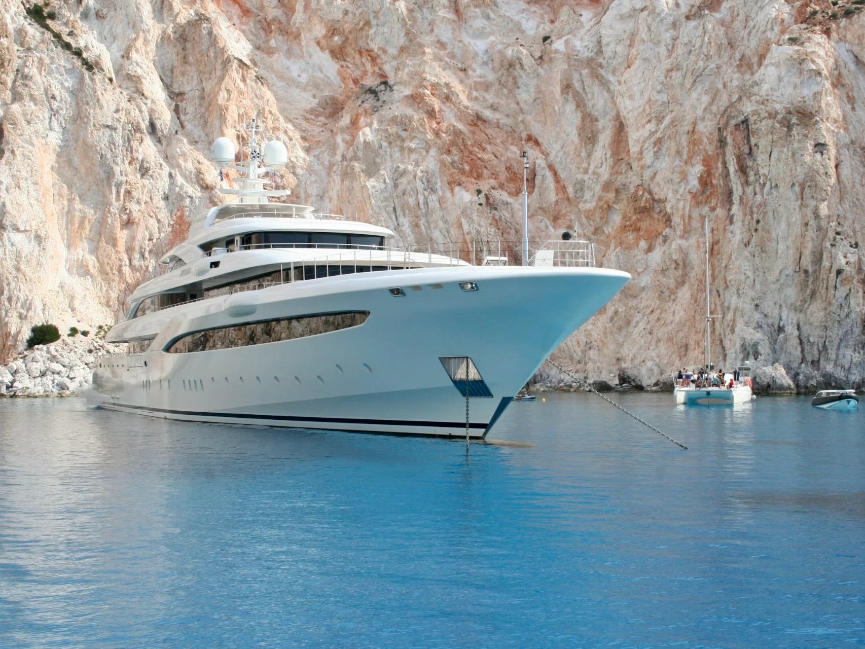 A private yacht anchored in turquoise water beneath rocky cliffs
